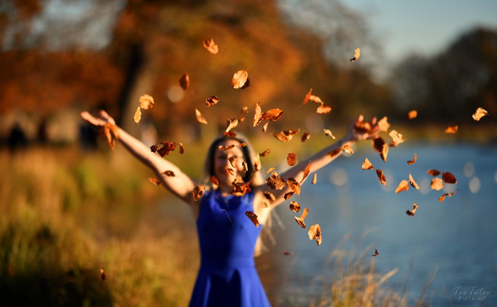 Woman throwing yellow leaves in the air